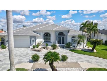 Beautiful white home featuring a well manicured front yard with elegant palm trees and stone driveway at 507 Monaco Dr, Punta Gorda, FL 33950
