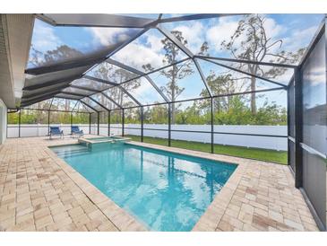 A beautiful screened-in pool with brick pavers and outdoor seating offers the perfect spot for relaxation and entertainment at 14325 Mcfarland Ave, Port Charlotte, FL 33981