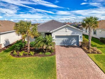 Charming single-story home featuring a brick driveway, well-kept lawn and beautiful tropical landscaping at 15033 Spanish Point Dr, Port Charlotte, FL 33981