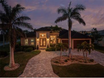 Elegant home featuring lush landscaping, stone driveway, and striking architecture under a twilight sky at 197 Colony Point Dr, Punta Gorda, FL 33950
