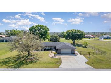 Well-manicured home with a large lawn, mature trees, and a paved driveway leading to an attached two-car garage at 31093 N Bend St, Punta Gorda, FL 33982