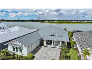 Stunning home with a lake view, lush landscaping, and a stylish gray metal roof at 42239 Lake Timber Dr, Punta Gorda, FL 33982
