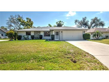 Charming single-story home featuring a well-manicured lawn and an attached two-car garage at 21229 Giddings Ave, Port Charlotte, FL 33952