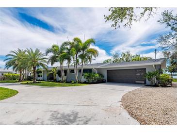 Charming single-story home featuring lush landscaping, modern garage door, and circular driveway at 75 Spyglass Aly, Placida, FL 33946