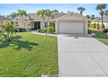 Charming single-story home with a well-manicured lawn, palm trees, and a two-car garage at 11 Mark Twain Ln, Rotonda West, FL 33947