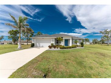 Charming single-story home featuring a well-manicured lawn, a bright blue front door and a spacious two car garage at 16271 Branco Dr, Punta Gorda, FL 33955