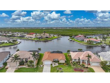 Aerial view showcasing a waterfront home with lush landscaping, situated on a canal, offering picturesque water access at 3961 San Pietro Ct, Punta Gorda, FL 33950