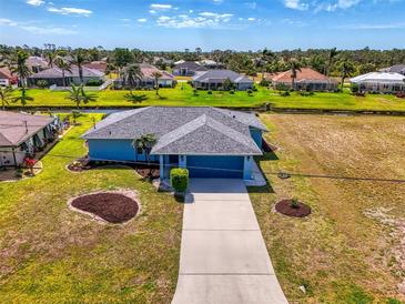 Charming single-story blue home featuring a gray roof, well-maintained landscaping, and a spacious driveway at 149 Sportsman Rd, Rotonda West, FL 33947