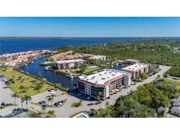 Stunning aerial view of waterfront condos with boat docks, lush landscaping, and beautiful bay views at 25188 Marion Ave # D303, Punta Gorda, FL 33950