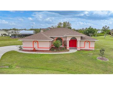 Charming single-story home with well-manicured lawn and bright red front door at 26389 Villa Maria Dr, Punta Gorda, FL 33983