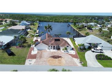 Beautiful waterfront home boasts a brick driveway and solar panels, with tropical landscaping at 4242 Rose Arbor Cir, Port Charlotte, FL 33948