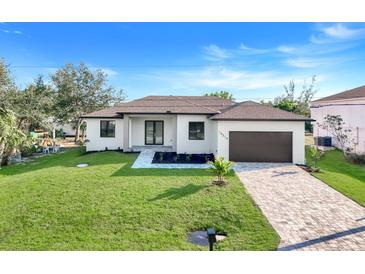 Charming single-story home with a well-manicured lawn, a paved driveway, and a two-car garage at 14319 Allensworth Ave, Port Charlotte, FL 33981