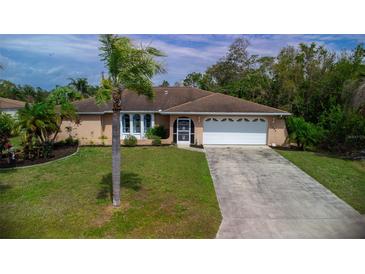 Charming single-story home featuring a manicured lawn, palm tree, and attached two-car garage at 22448 Tennyson Ave, Port Charlotte, FL 33954