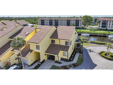 Inviting two-story yellow townhouse with a brick driveway, an attached garage, and waterway access with boats at 25188 Marion Ave # 1015, Punta Gorda, FL 33950