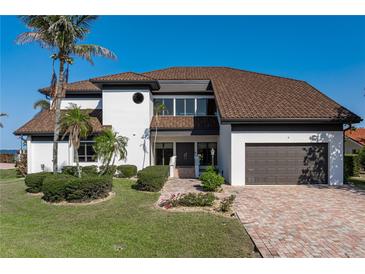 Beautiful two-story home with a well-manicured lawn, brick driveway, and attached two car garage at 8 Ocean Dr, Punta Gorda, FL 33950