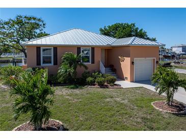 Charming waterfront home featuring a durable metal roof, lush landscaping, and a convenient one-car garage at 721 Dania Ct, Punta Gorda, FL 33950