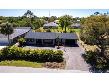 Aerial view of a single story home featuring a driveway and manicured landscaping in a lush neighborhood at 23179 Maclellan Ave, Port Charlotte, FL 33980