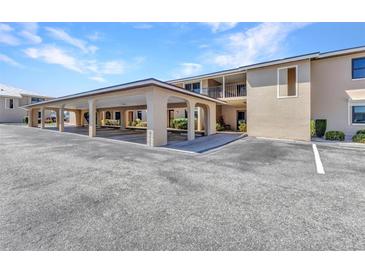 Condo building featuring covered parking, beige exterior, and well-maintained landscaping at 240 Lewis Cir # 28, Punta Gorda, FL 33950