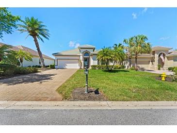 Beautiful home featuring a well-manicured lawn, brick driveway and mature palm trees in desirable community at 13352 Creekside Ln, Port Charlotte, FL 33953