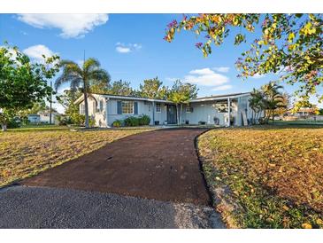 Charming single-story home featuring a long driveway, well-maintained lawn, and beautiful mature landscaping at 146 Francis Ne Dr, Port Charlotte, FL 33952