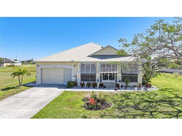Charming single-story home featuring lush landscaping, a well-maintained lawn, and a metal roof at 17408 Malarky Ln, Punta Gorda, FL 33955