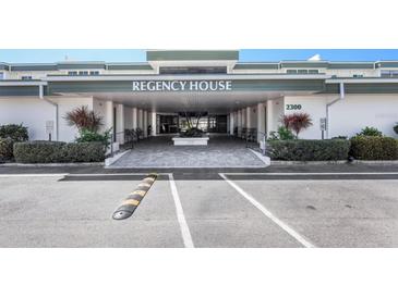 Welcoming entrance to Regency House with covered drive, well-maintained landscaping, and ample parking at 2300 Aaron St # 106, Port Charlotte, FL 33952