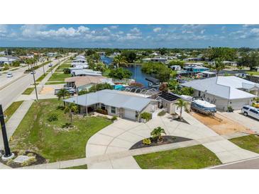 Waterfront property featuring mature landscaping, circular driveway, and boat parking in a quiet neighborhood at 21194 Edgewater Dr, Port Charlotte, FL 33952