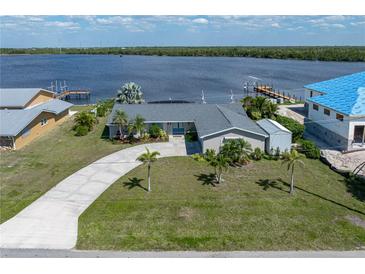 Expansive aerial view of a waterfront property, featuring lush landscaping and a private dock against a serene water backdrop at 2308 Harbour Dr, Punta Gorda, FL 33983