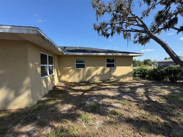 The backyard of the home has sparse grass and a tree providing shade at 30147 Holly Rd, Punta Gorda, FL 33982