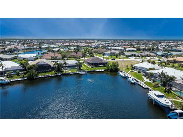 Aerial view showcasing a waterfront community with homes, canals, and boat docks under a clear blue sky at 3606 Whippoorwill Blvd, Punta Gorda, FL 33950