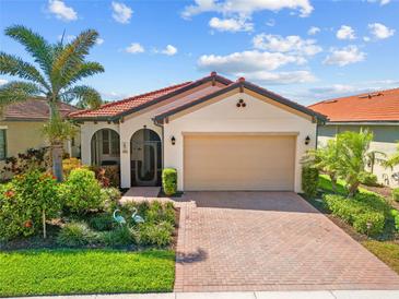 Beautiful single-Gathering home with lush landscaping, brick driveway, and a beige stucco exterior at 10357 Crooked Creek Dr, Venice, FL 34293