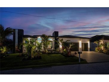 Contemporary home showcasing professional landscaping, a two-car garage, and modern architectural elements at twilight at 1230 Royal Tern Dr, Punta Gorda, FL 33950