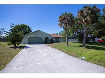 Charming single-story home featuring a long driveway, two-car garage, and mature palm trees at 23051 Elmira Blvd, Punta Gorda, FL 33980