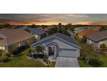 Inviting single-story home with a two-car garage, complemented by a well-maintained lawn and tropical landscaping at sunset at 24055 Buckingham Way, Punta Gorda, FL 33980