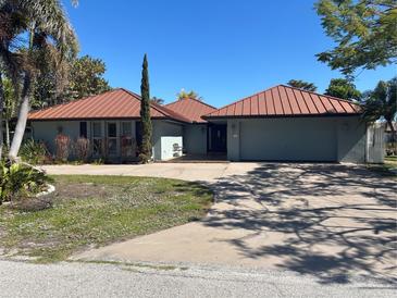 Charming single-story home with a copper-colored metal roof, a two-car garage, and mature landscaping in a sunny neighborhood at 104 Graham Se St, Port Charlotte, FL 33952