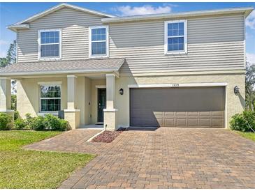 Inviting two-story home featuring a brick driveway, neutral siding, and an attached two-car garage at 15172 Mcgraw Ave, Port Charlotte, FL 33953