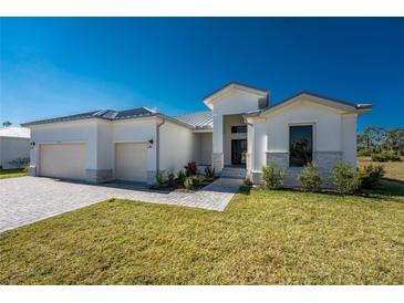 Beautiful home featuring a well-manicured lawn and a three-car garage, providing ample space for vehicles and storage at 17476 Vellum Cir, Punta Gorda, FL 33955