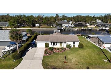 Charming waterfront home with attached garage, lush landscaping, and well-manicured lawn at 18427 Goodman Cir, Port Charlotte, FL 33948