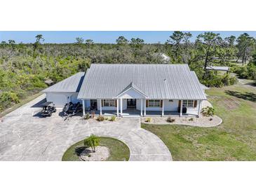 Charming single-story home with a metal roof, circular driveway, and a beautifully landscaped front yard at 16180 Forest Glen Ct, Punta Gorda, FL 33982