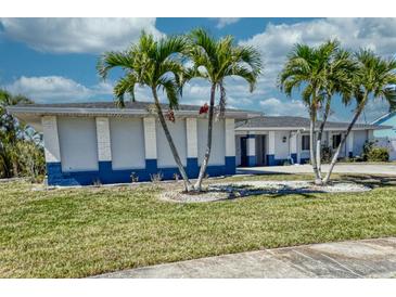 Inviting single-story home with vibrant blue trim and well-manicured lawn adorned with lovely palm trees at 234 Tait Se Ter, Port Charlotte, FL 33952