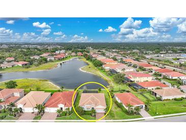 An aerial view showcases a home with a lake view, surrounded by lush landscaping, and a backdrop of other homes and trees at 24407 Riverfront Dr, Punta Gorda, FL 33980