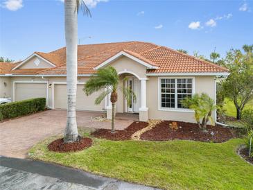 Charming single-story home featuring a well-manicured lawn, brick driveway, and a terracotta roof at 16308 Sunset Palms Blvd # 1702, Punta Gorda, FL 33955