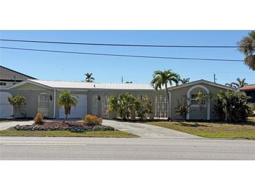 Inviting single-story home with a well-manicured front yard featuring lush landscaping and a concrete driveway at 285 Bal Harbor Blvd, Punta Gorda, FL 33950