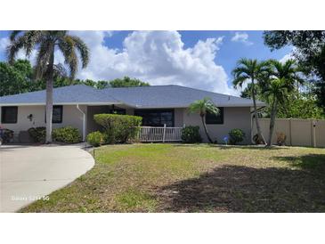 Charming home featuring a well-maintained lawn, mature trees, and a freshly painted exterior in a serene setting at 131 Spring Lake Nw Blvd, Port Charlotte, FL 33952