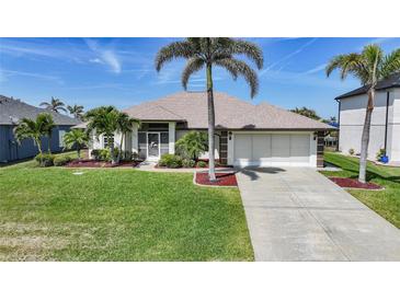 Charming single-story home with a well-manicured lawn, beautiful landscaping, and a two-car garage at 15538 Aqua Cir, Port Charlotte, FL 33981