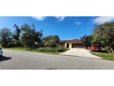 Charming single-story home featuring a two-car garage and a spacious driveway amidst lush, mature landscaping at 3357 Vassar St, Port Charlotte, FL 33980