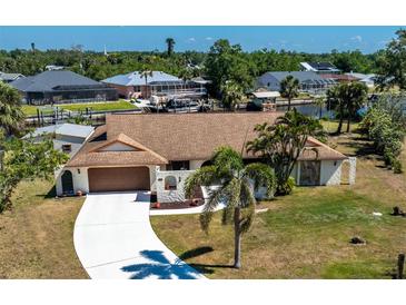 Charming waterfront home featuring a well-manicured lawn, concrete driveway, and beautiful canal views at 18584 Alphonse Cir, Port Charlotte, FL 33948