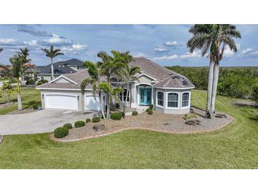 Charming single-story home with a well-manicured lawn, palm trees, and a colorful front door at 19023 Midway Blvd, Port Charlotte, FL 33948