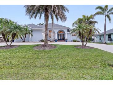 Inviting single-Gathering home featuring a beautifully landscaped front yard and a charming blue exterior with palm trees at 1091 Rotonda Cir, Rotonda West, FL 33947