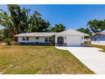 Charming single-story home with a well-maintained lawn and a new driveway leading to an attached garage at 1357 Nimrod St, Port Charlotte, FL 33952